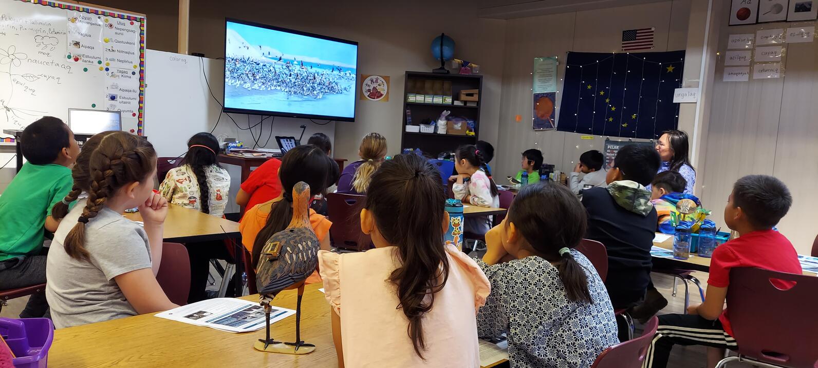Children in classroom setting watching a screen