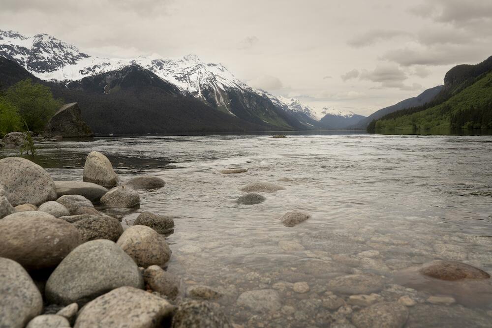 Body of water before mountains with cloudy skies