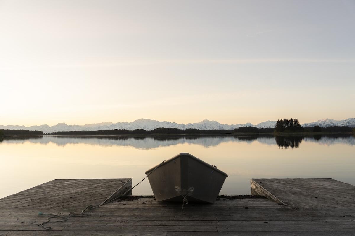 Small boat at dock with snowy mountains in background