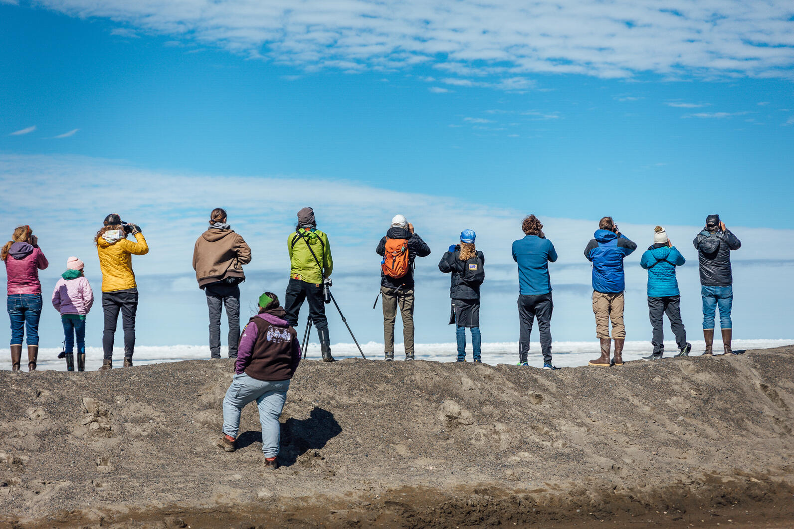 Multiple people lined up on coast with scopes Multiple people lined up on coast with scopes