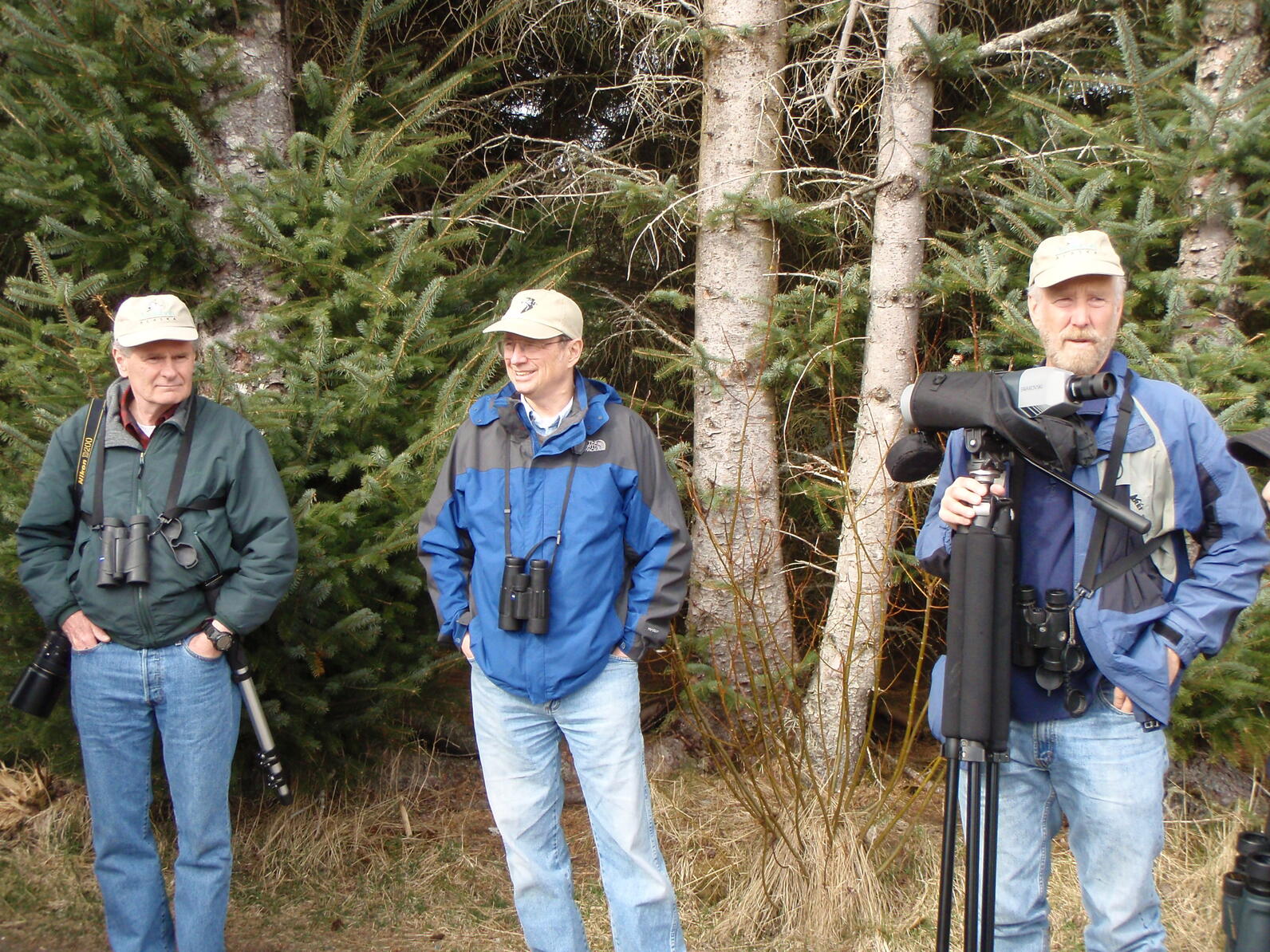 Three men standing in front of trees