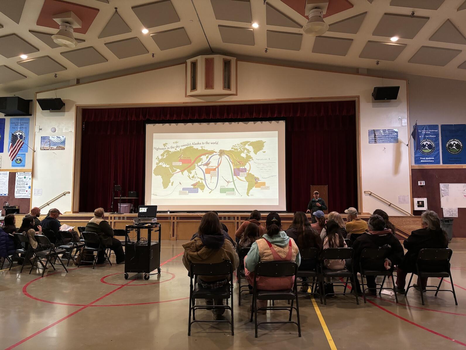 Presentation held in an auditorium with audience and presenter showing flyways Presentation held in an auditorium with audience and presenter showing flyways