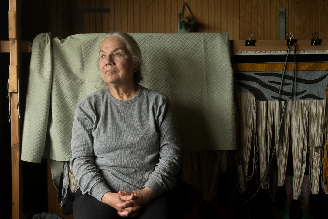 Woman sitting next to weaving looking out window