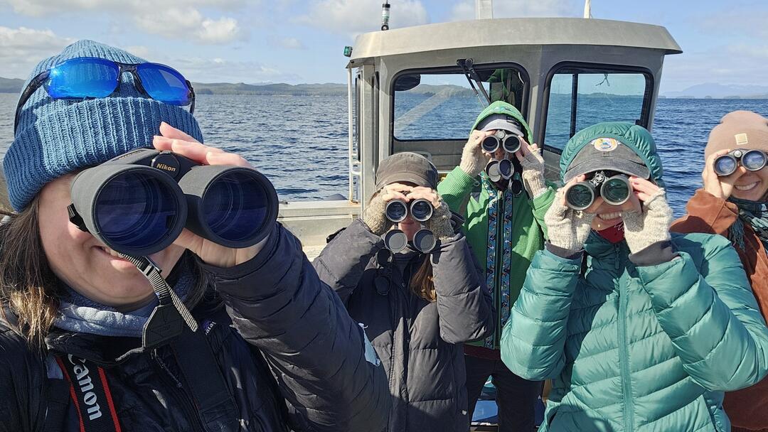 Five people with binoculars on boat